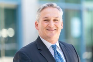 man smiling, wearing blue tie, blue sport coat and white dress shirt