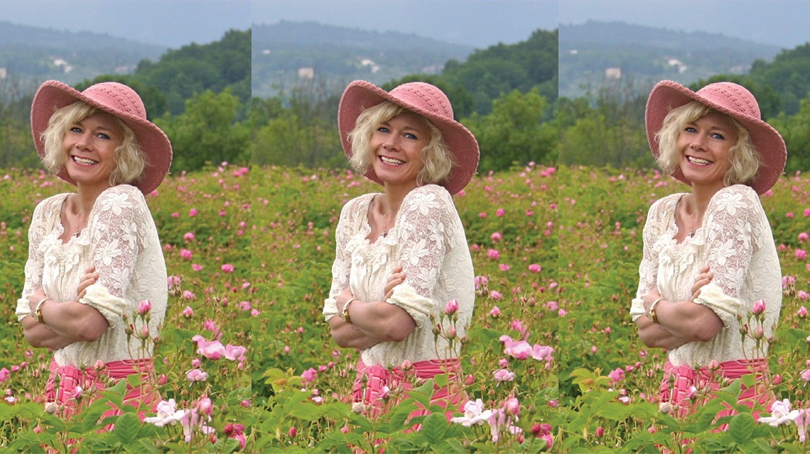 woman smiling, standing among pink flowers
