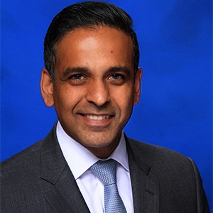 A man in a suit smiles looking into the camera