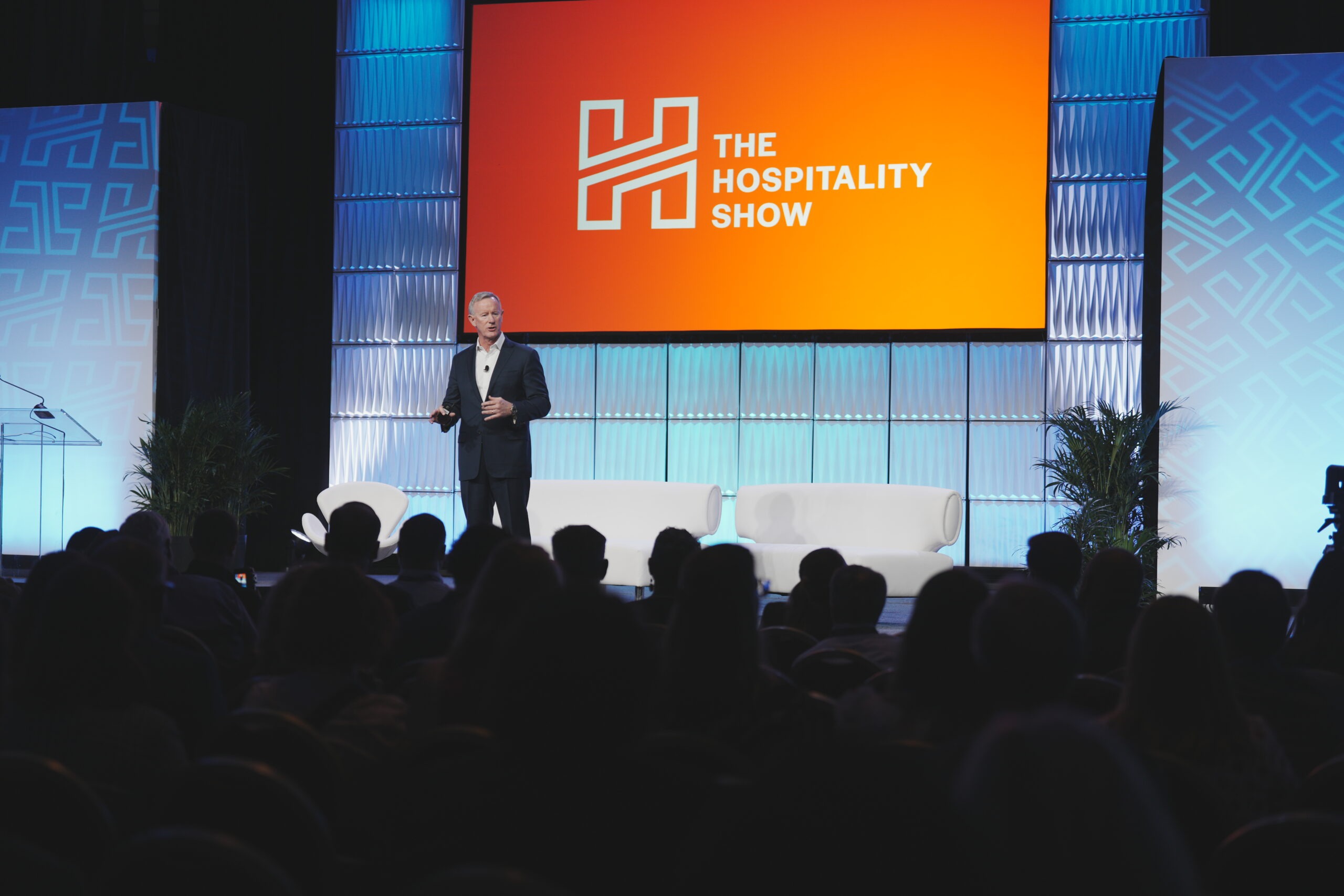 wide shot of man on stage, crowd in foreground