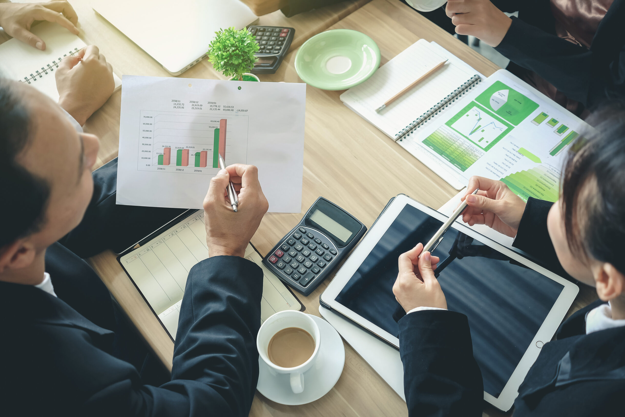 professionals sit around a table to view statistic results, alongside greenery