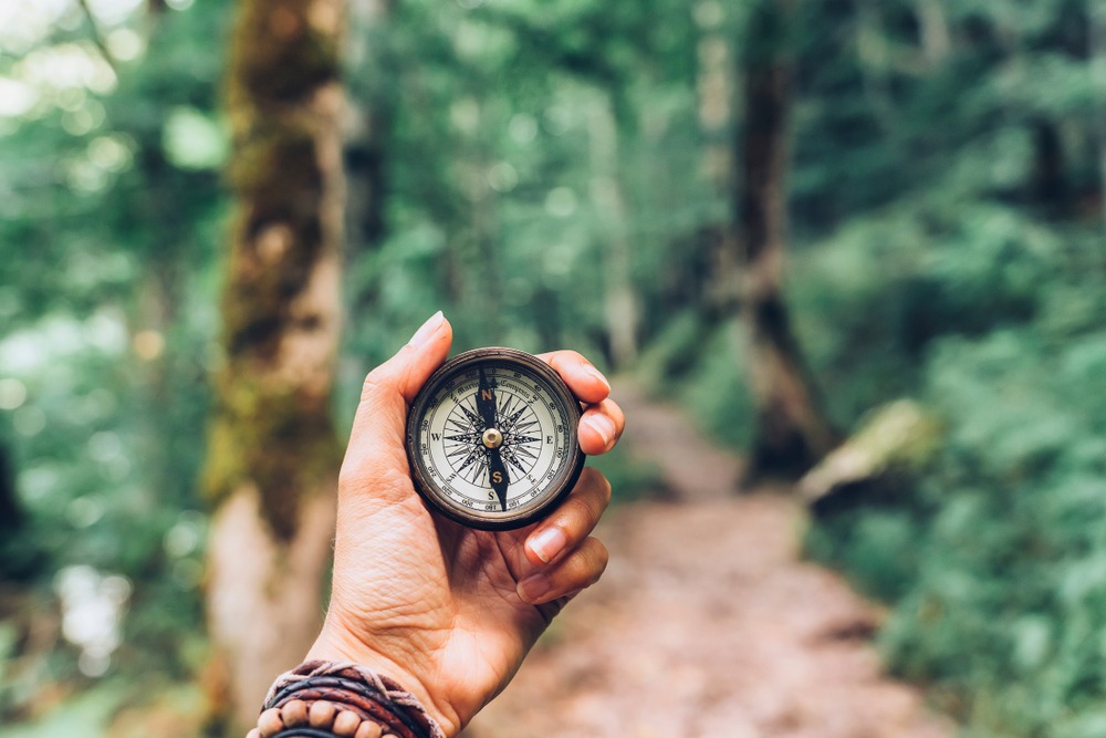 Lost woman on the mountain, orienting herself with a compass