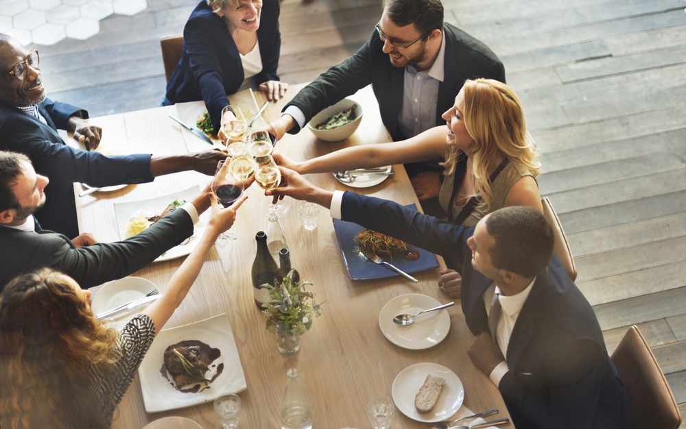 businesspeople clinking glasses at table