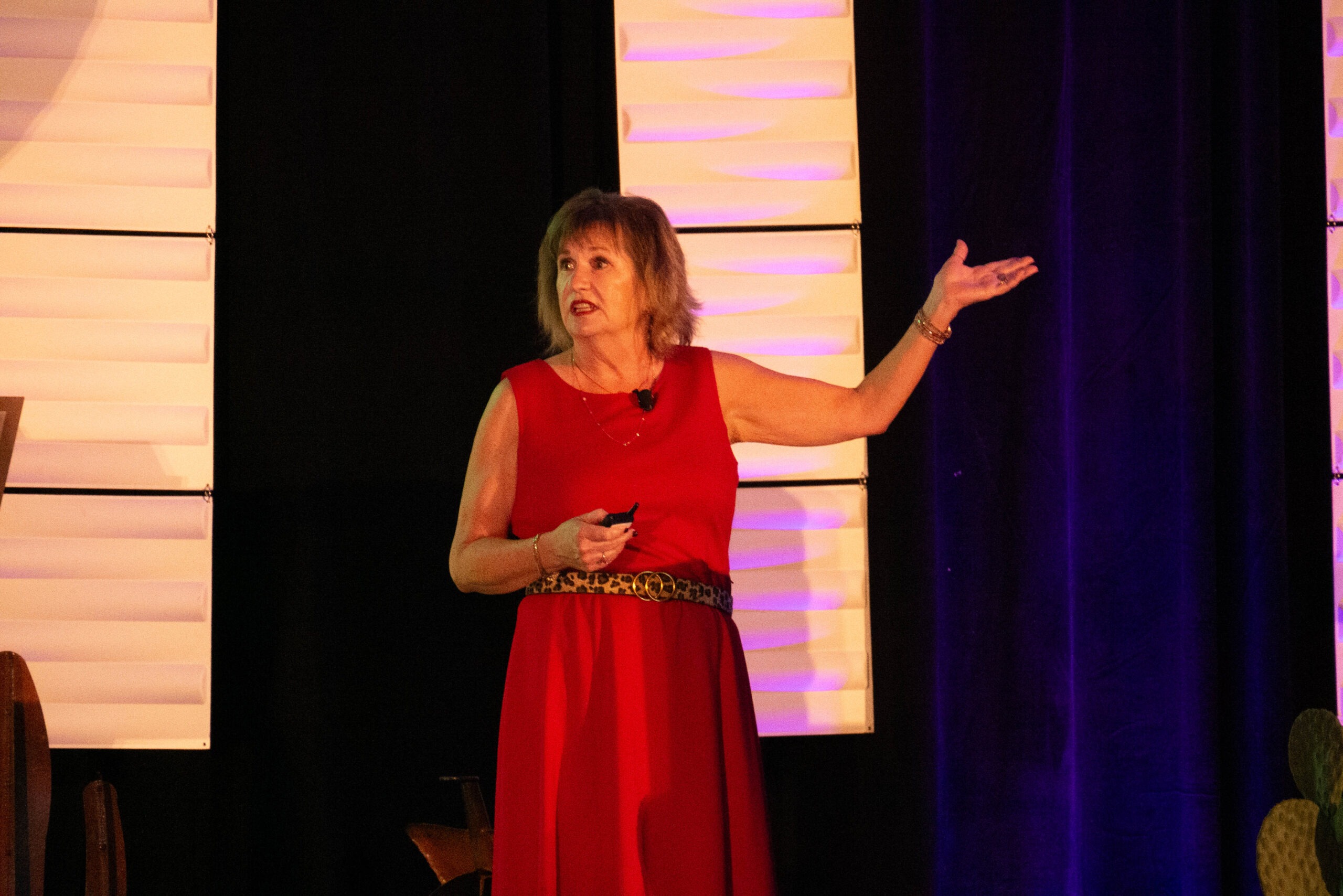 woman in red dress on stage talking to crowd