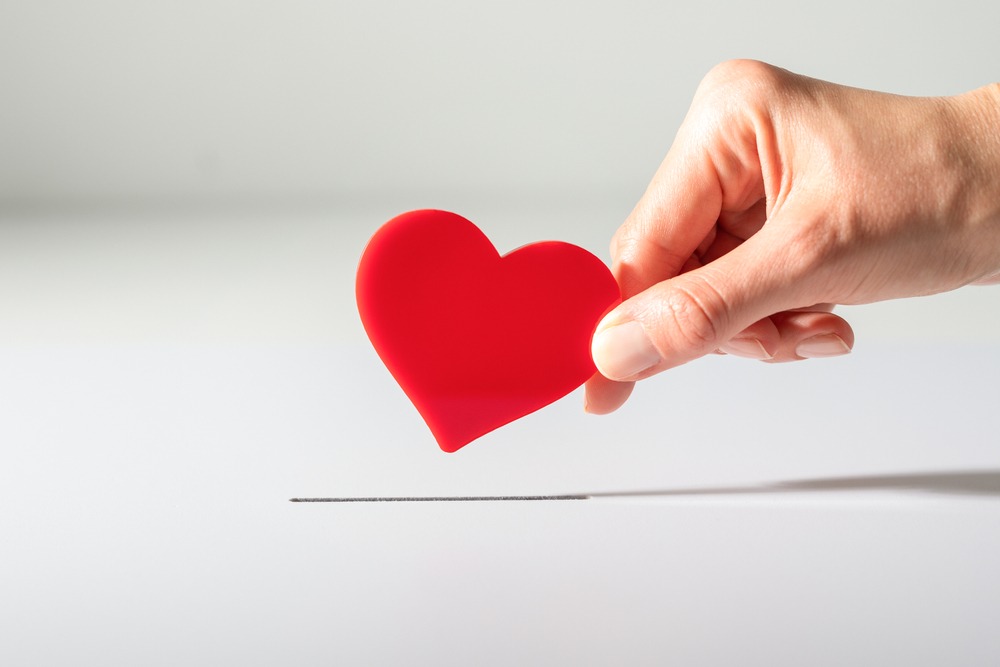 Woman’s hand places heart in the donation slot