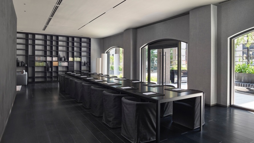 a conference room at Hotel AKA Alexandria has neutral colored walls, wooden flooring, big windows, and comfortable chairs around a long rectangular table