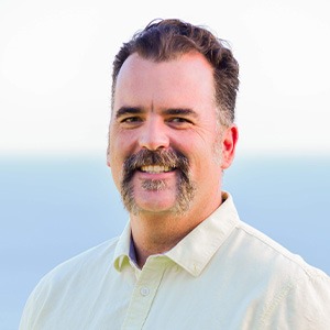 man smiling, wearing yellow button up shirt