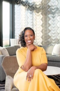 Woman in yellow dress in elegant white hotel room smiling at camera