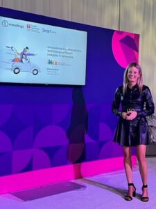 Tracy Judge in front of purple wall with monitor.