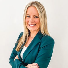 Tracy Judge, CEO of Soundings, smiling with crossed arms in teal jacket.