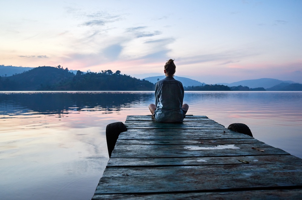 woman sitting on dock at sunset 