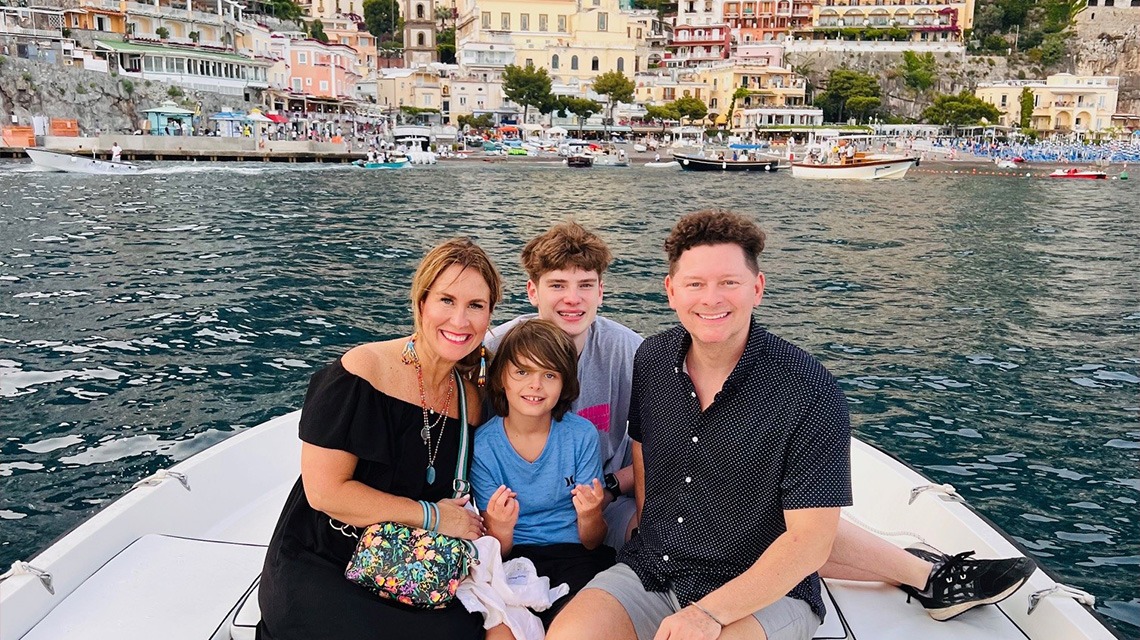 family of four on small boat posing for picture in front of city