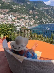woman relaxing on patio in front of beach and homes on hill