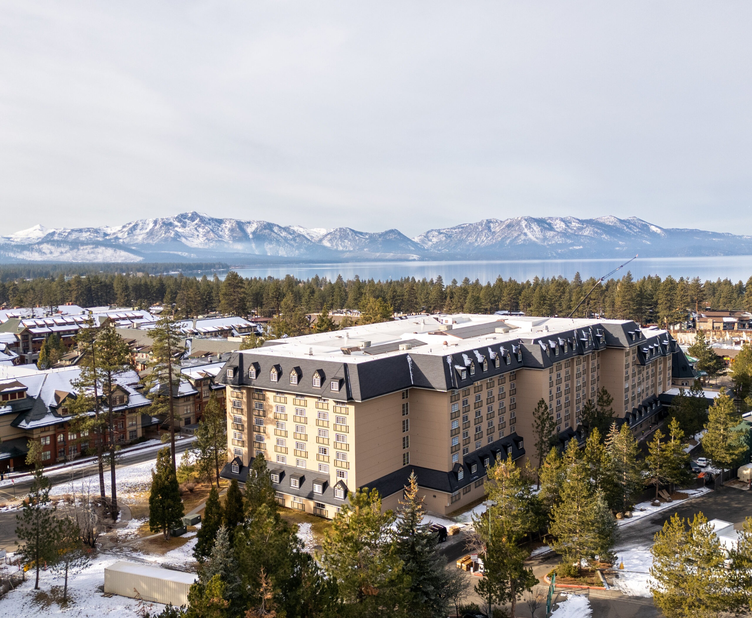 aerial shot of hotel with mountains and lake in background
