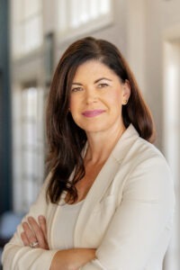 woman in white long sleeve shirt crossing arms and smiling
