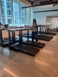 woman walking on treadmill while working on computer