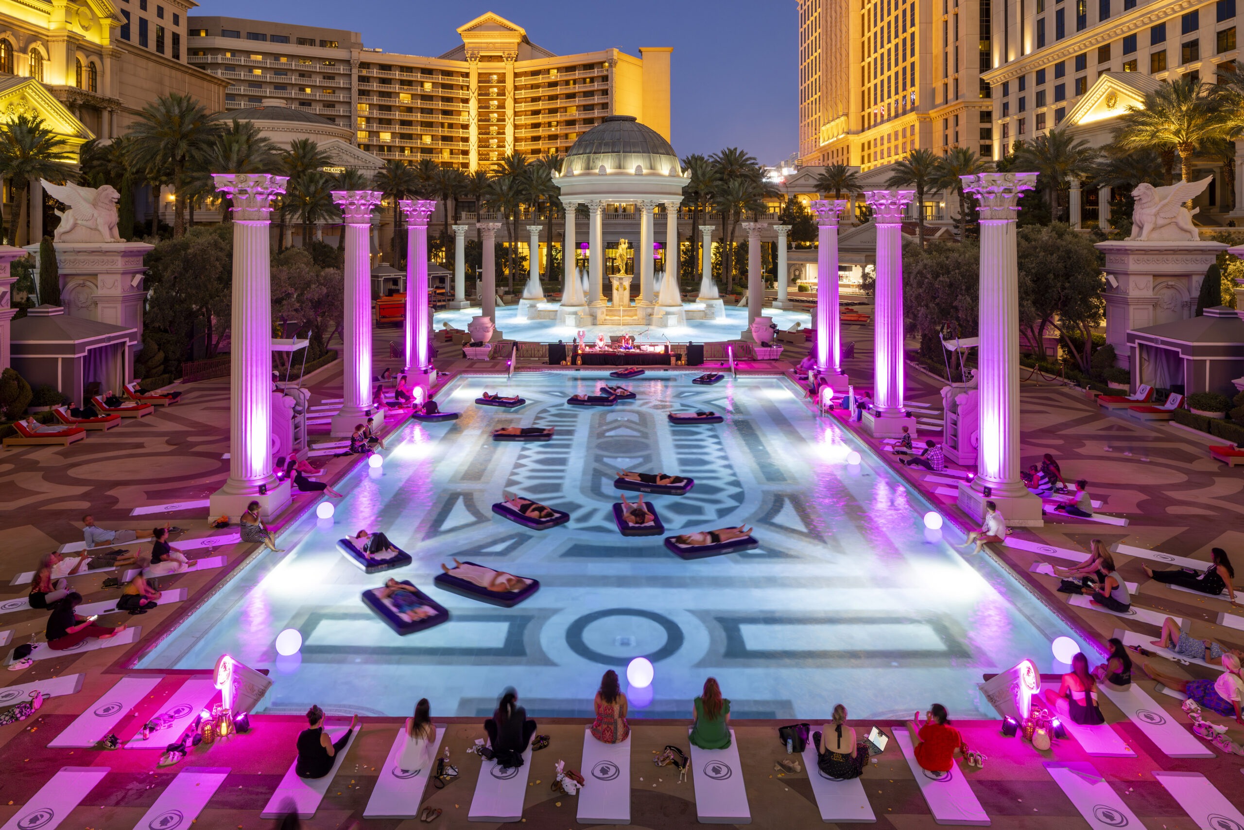 people floating in hotel pool surrounded by purple lights