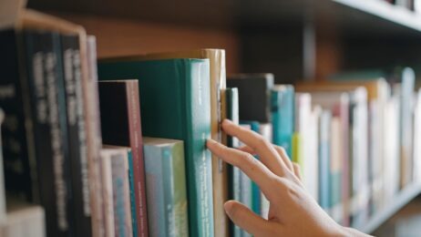 Close up hand search for book on bookshelves in the library