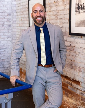 Frank Carlisi in blue dress shirt, grey suit and tie