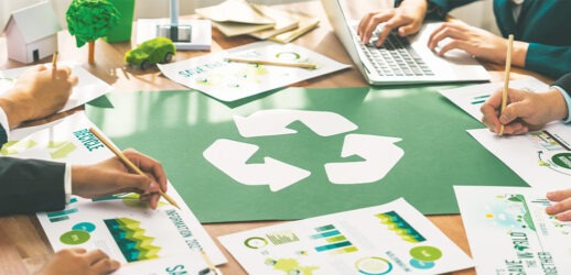 Businesspeople writing at table with recycling sign on it