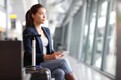 woman with phone in airport waiting for uber rideshare