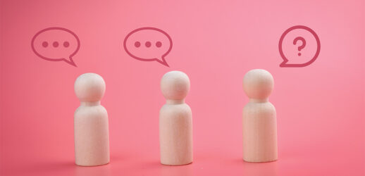 Wooden figures talking against pink background