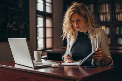 Woman sitting at desk looking in notebook