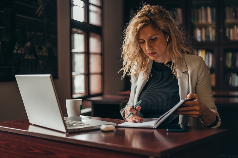 Woman sitting at desk looking in notebook