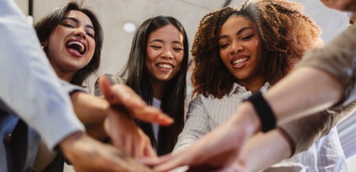 Female coworkers joining hands