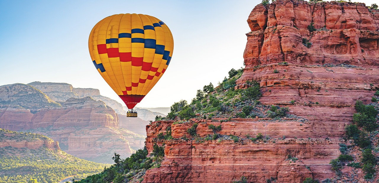 A hot air balloon hovers near Red Rock Mountain