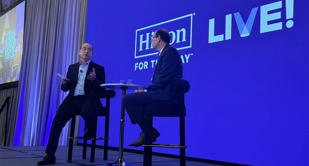 People on stage with Hilton sign behind them