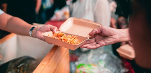 One person handing box of food to another person