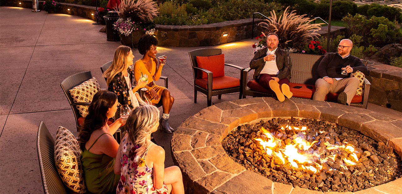 Coworkers sitting around fire pit at Tetherow Resort