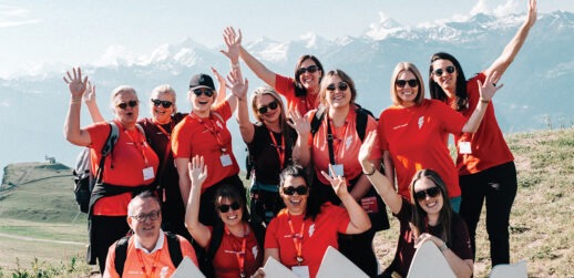 People in red shirts posing in front of a mountain