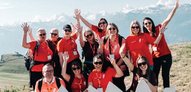 People in red shirts posing in front of a mountain