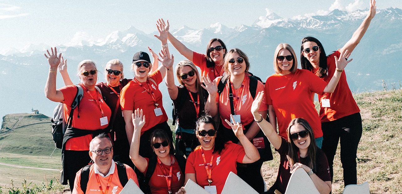 People in red shirts posing in front of a mountain