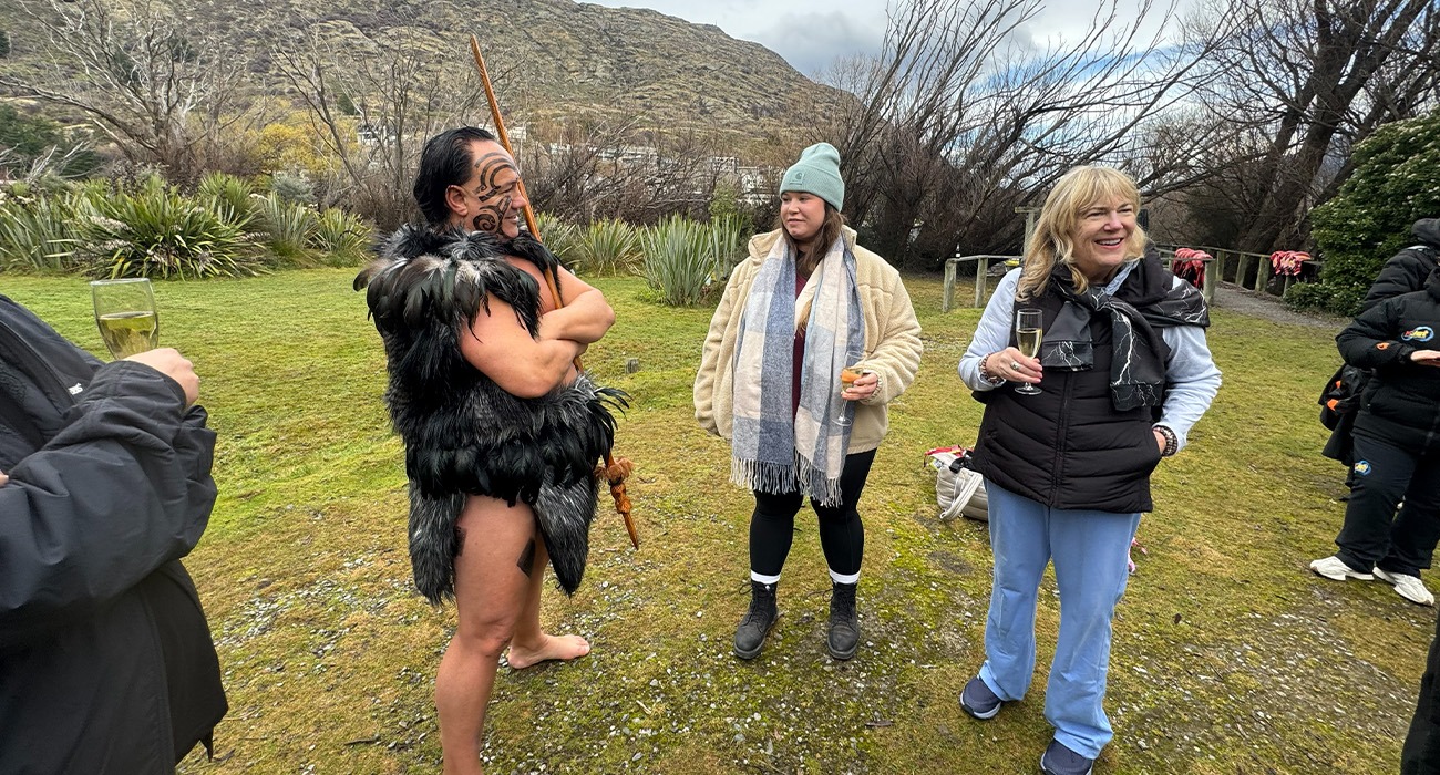 Three people talking outside in front of mountain