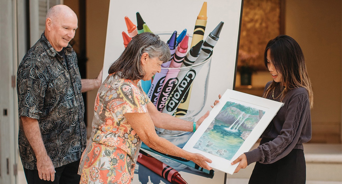 A woman holding a painting of a waterfall