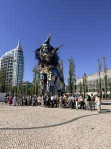 People standing next to large cat sculpture