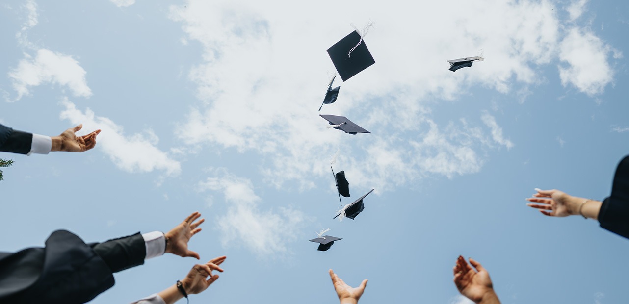 Students throwing graduation hats into sky