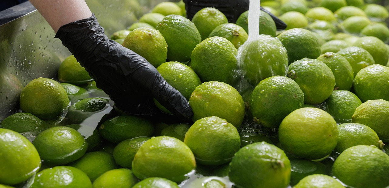 Person with black gloves washing limes